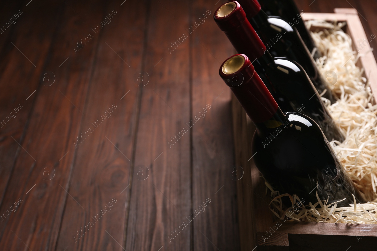 Photo of Crate with bottles of wine on wooden table. Space for text