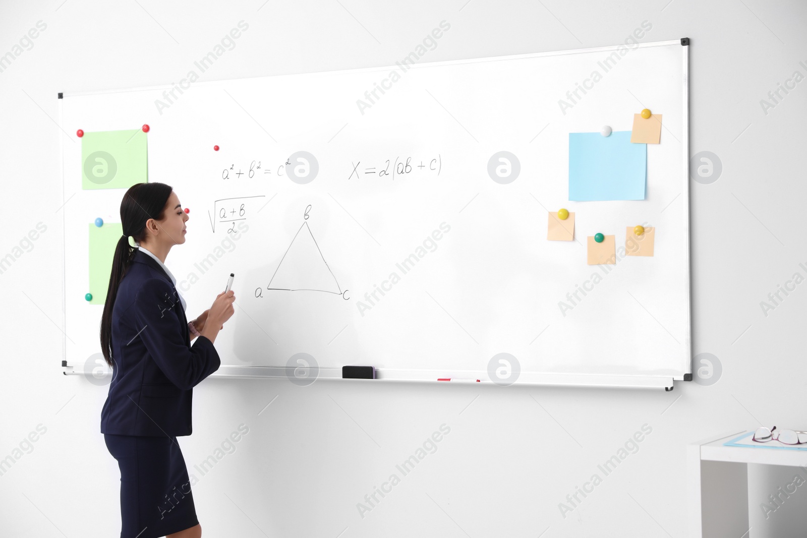 Photo of Young teacher near whiteboard in modern classroom