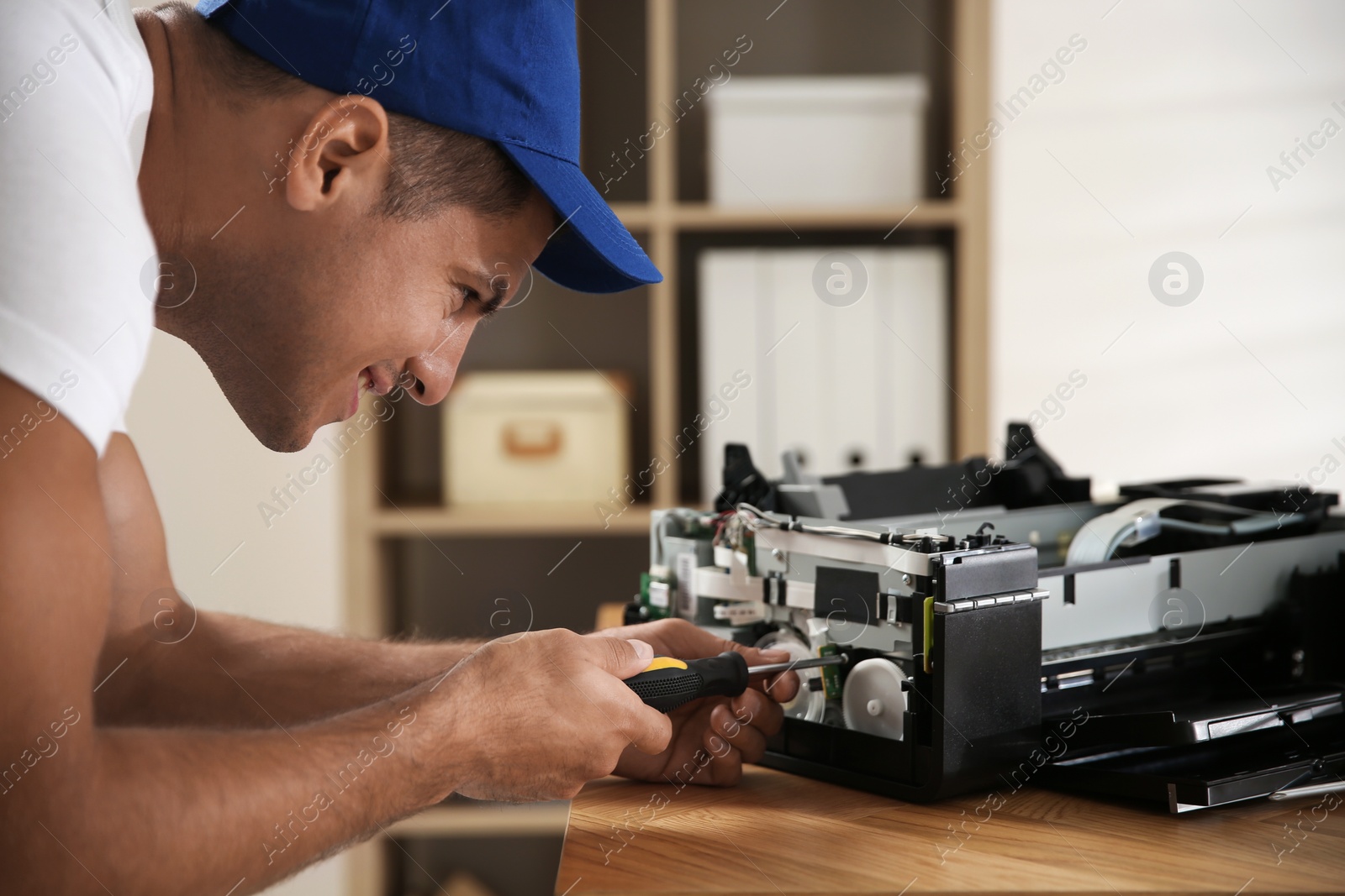 Photo of Repairman with screwdriver fixing modern printer in office