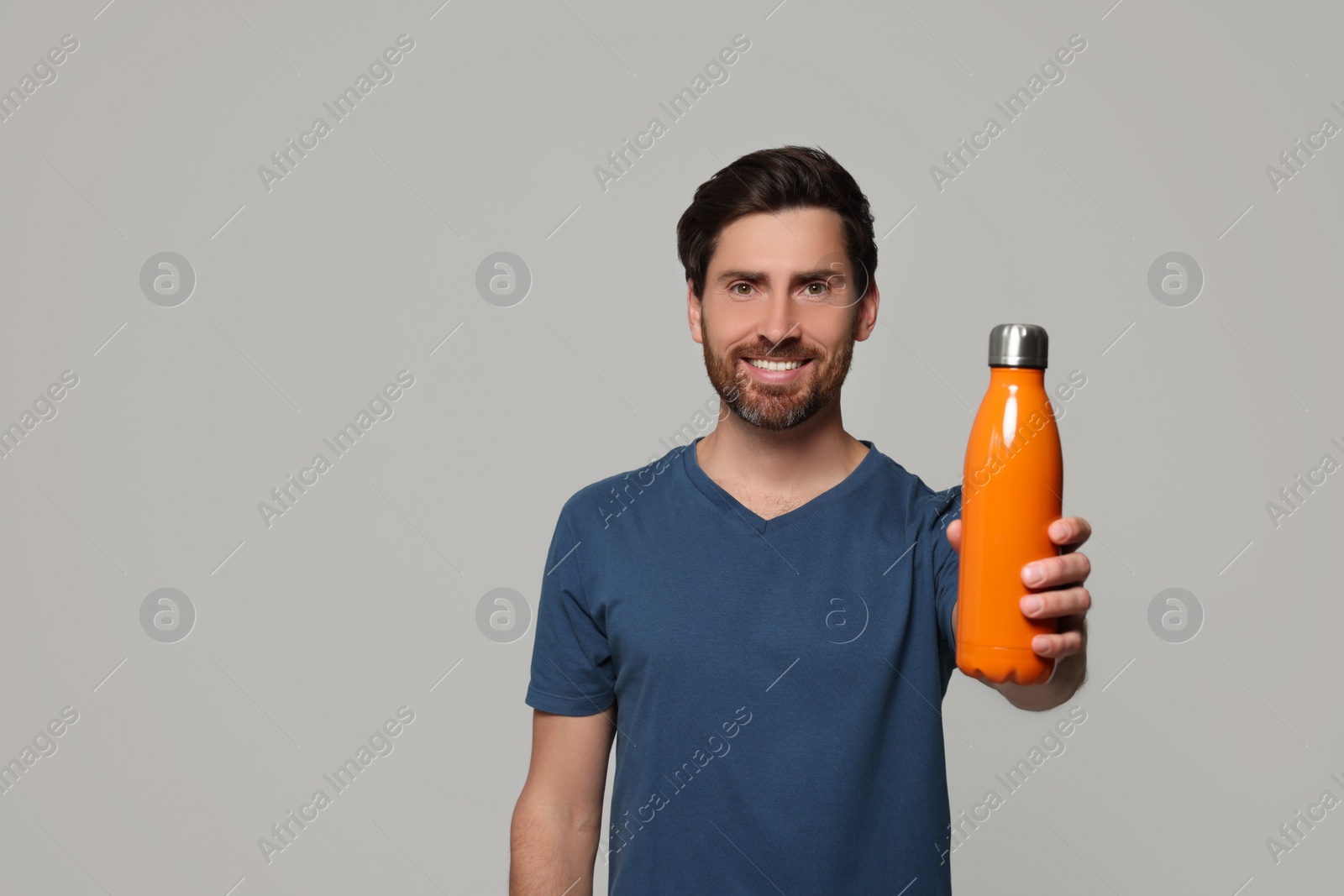 Photo of Man with orange thermo bottle on light grey background. Space for text