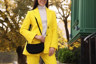 Fashionable young woman with stylish bag on city street, closeup. Space for text