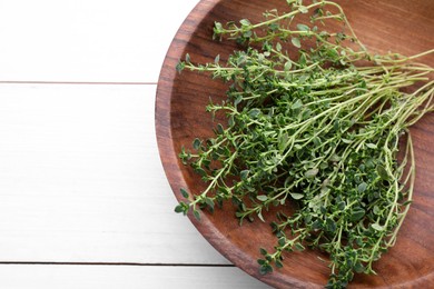 Bowl with aromatic green thyme on white wooden table, top view. Space for text