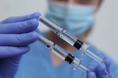 Photo of Doctor holding syringes with COVID-19 vaccine, closeup