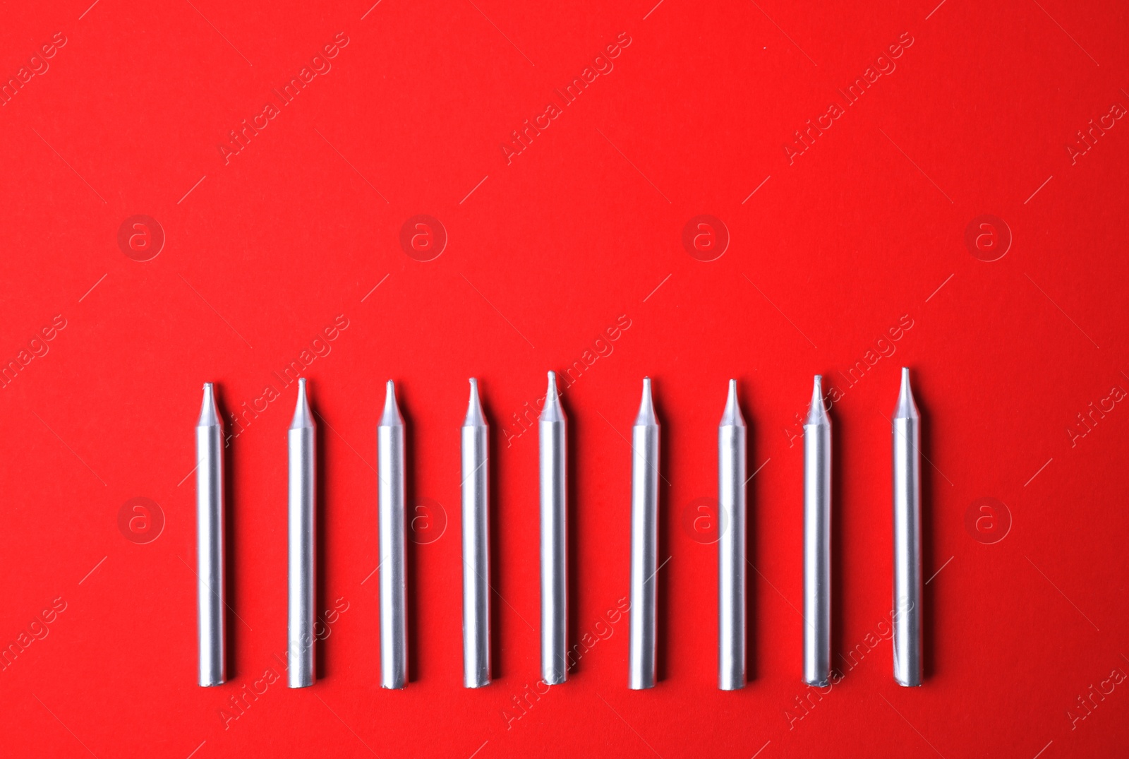 Photo of Silver birthday candles on red background, top view with space for text