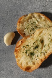 Photo of Tasty baguette with garlic and dill on grey textured table, flat lay