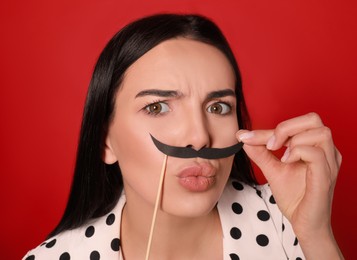 Photo of Funny woman with fake mustache on red background