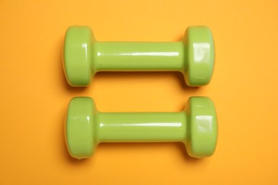 Photo of Dumbbells on orange background, flat lay. Sport equipment
