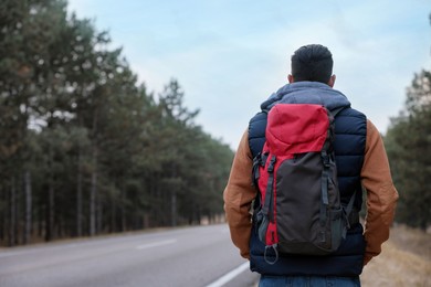 Photo of Man with backpack on road near forest, back view