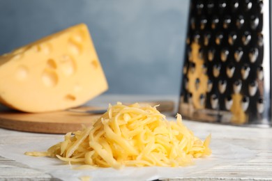 Photo of Tasty grated cheese on white wooden table, closeup