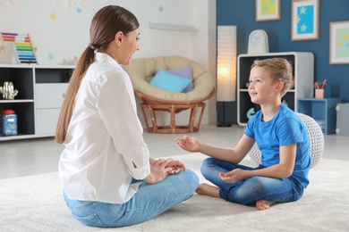 Female psychologist working with cute little boy in office