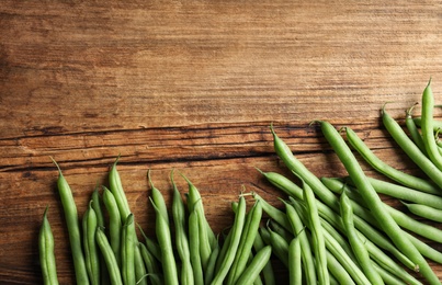 Photo of Fresh green beans on wooden table, flat lay. Space for text