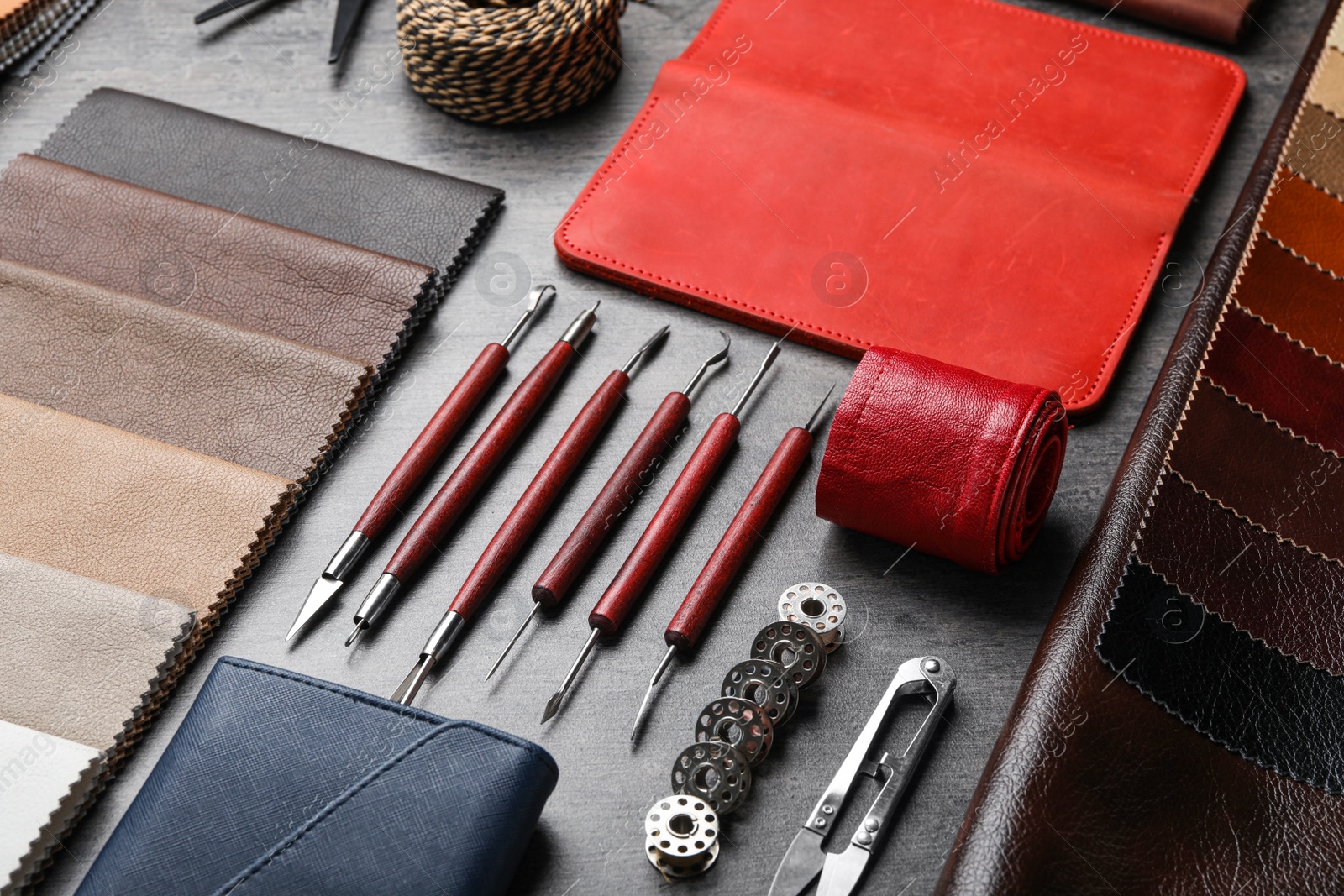 Photo of Leather samples and craftsman tools on grey stone background