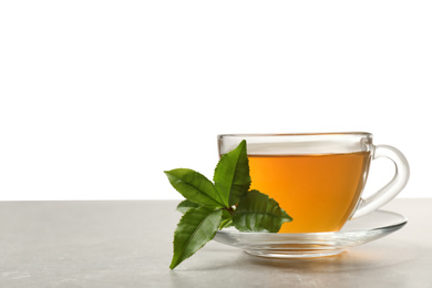 Photo of Cup of green tea and leaves on grey table