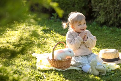 Photo of Happy little girl with cute rabbit on green grass outdoors
