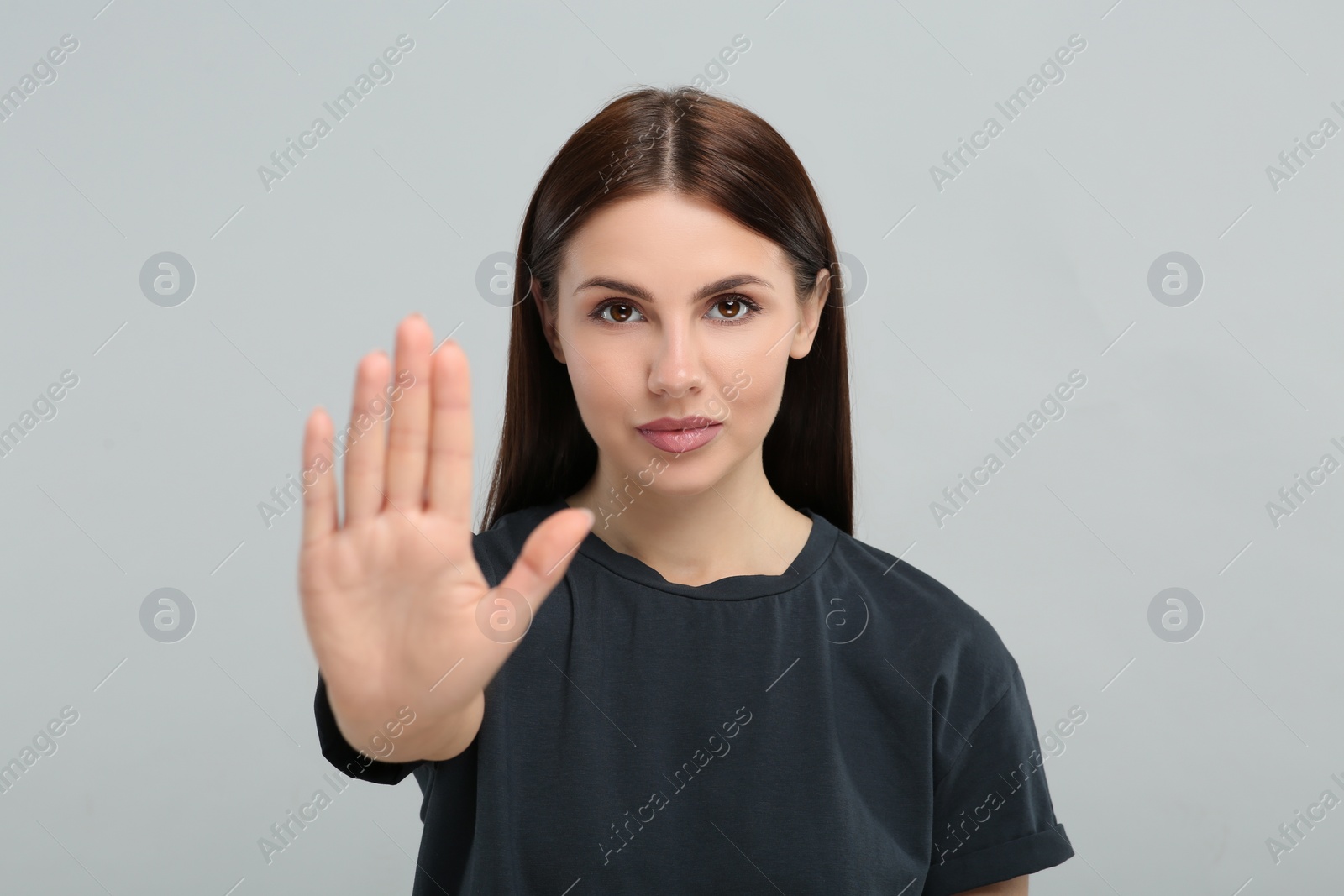 Photo of Woman showing stop gesture on grey background