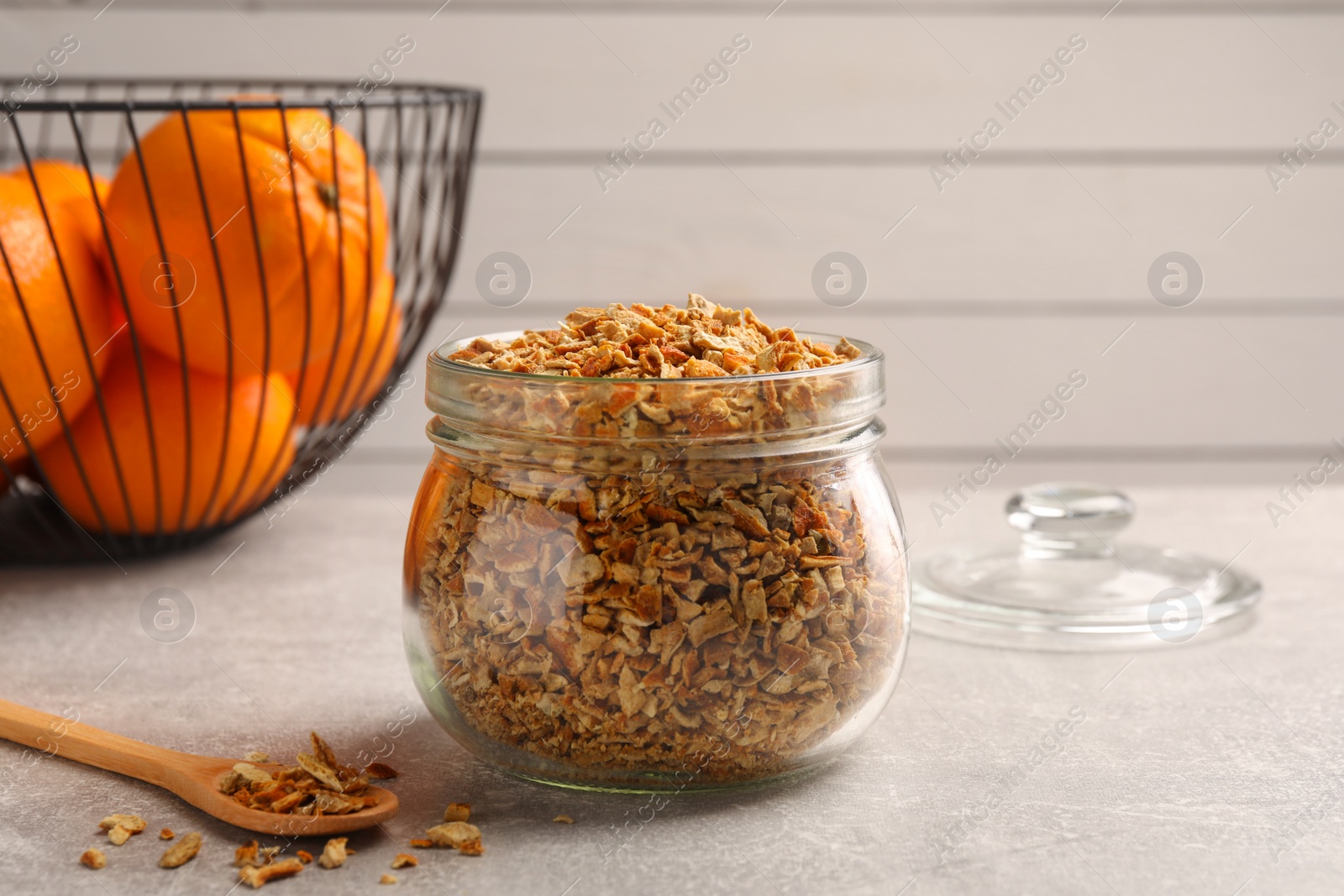 Photo of Jar of dried orange zest seasoning and fresh fruits on light grey table