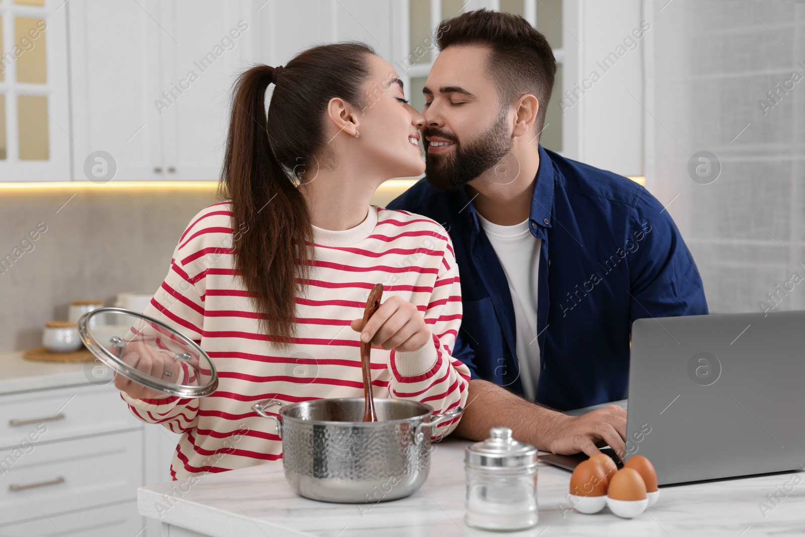 Photo of Happy lovely couple enjoying time together while cooking in kitchen