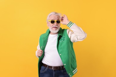 Photo of Portrait of grandpa with stylish sunglasses on yellow background