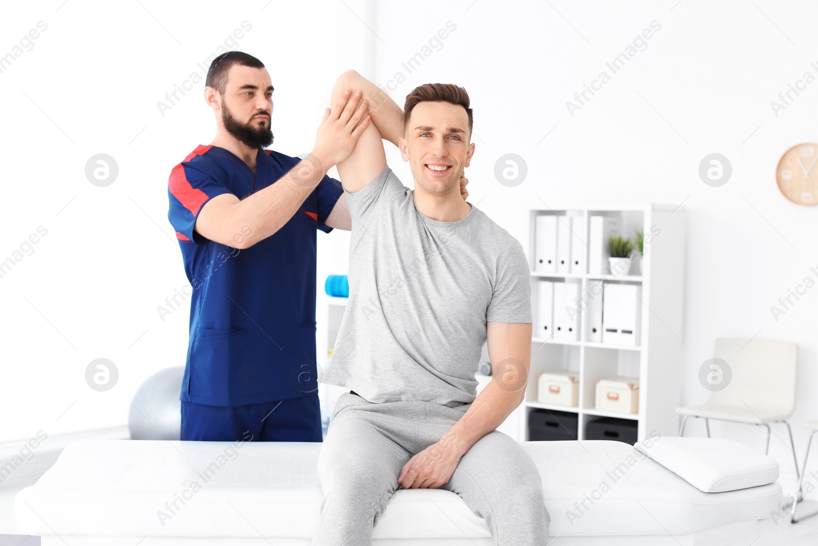 Photo of Physiotherapist working with young male patient in clinic