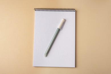 Notepad with erasable pen on beige background, top view
