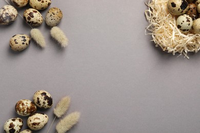 Photo of Speckled quail eggs and dry flowers on light grey background, flat lay. Space for text