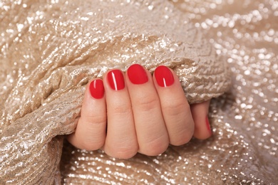 Photo of Woman with red manicure holding gold fabric, closeup. Nail polish trends