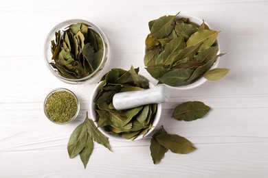 Photo of Whole and ground bay leaves on white wooden table, flat lay