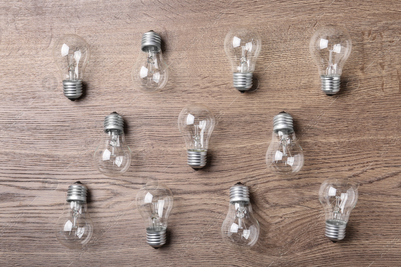 Photo of New incandescent lamp bulbs on wooden background, top view