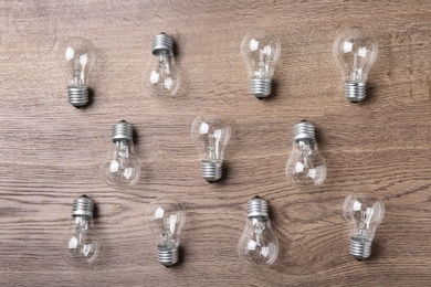 Photo of New incandescent lamp bulbs on wooden background, top view