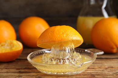 Photo of Cut fresh ripe orange and squeezer on wooden table, closeup