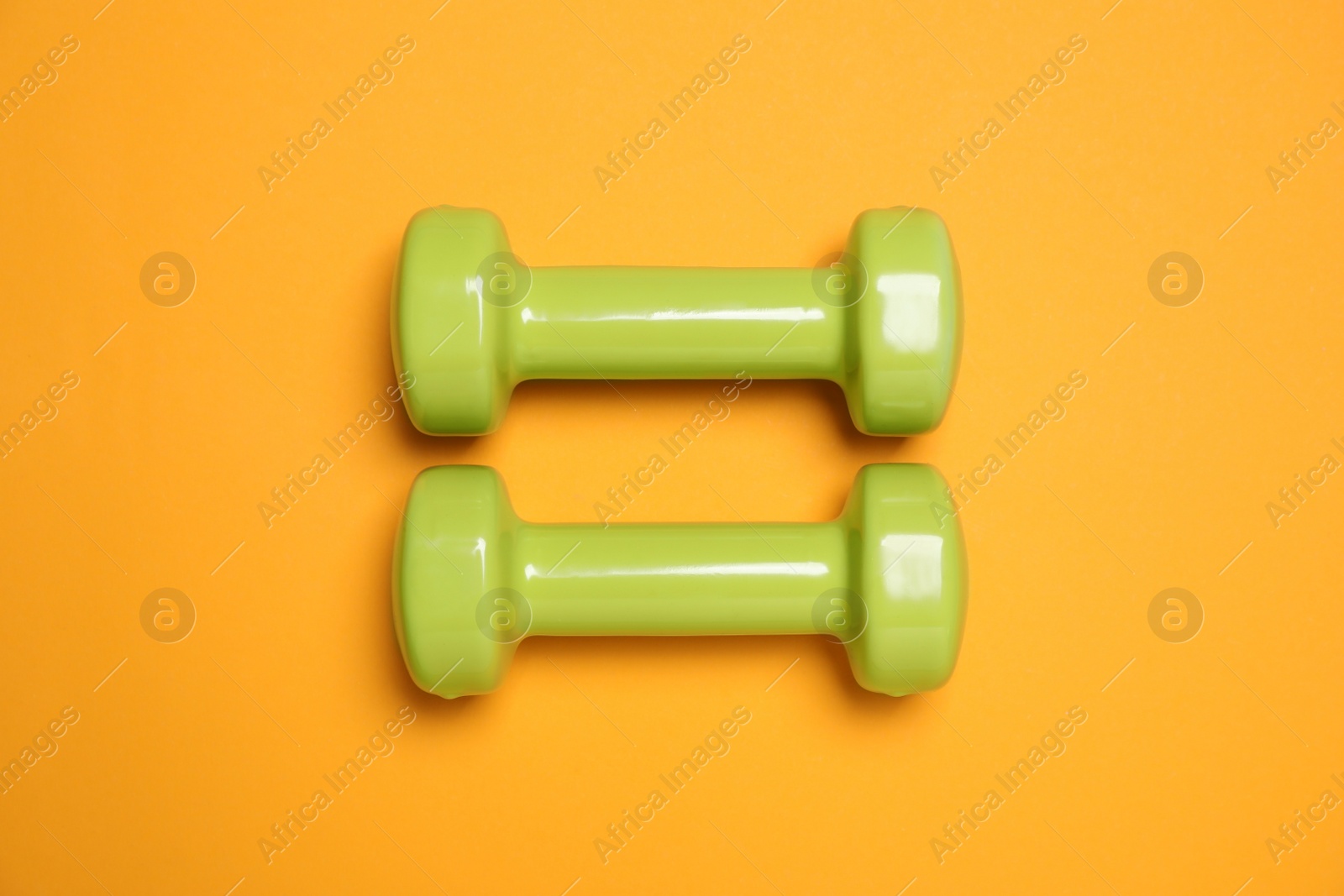 Photo of Dumbbells on orange background, flat lay. Sport equipment