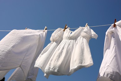 Photo of Clean clothes hanging on washing line against sky, low angle view. Drying laundry