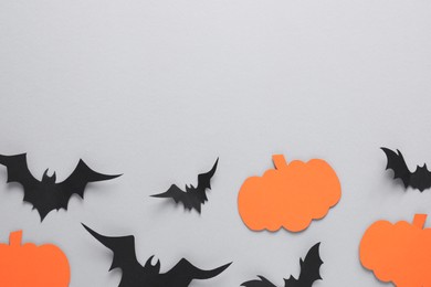 Photo of Flat lay composition with paper bats and pumpkins on light grey background, space for text. Halloween decor