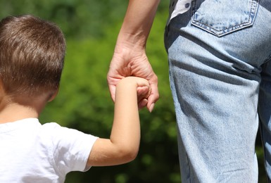 Mom and her child holding hands in park, closeup