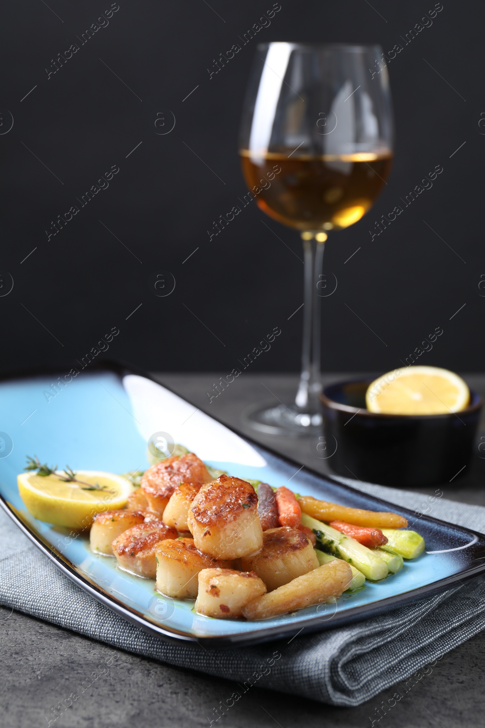 Photo of Delicious fried scallops with asparagus served on grey table