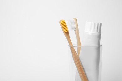 Photo of Glass with brushes and toothpaste on white background. Space for text