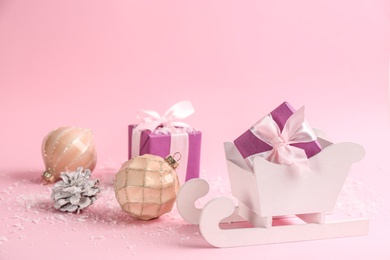 Photo of Beautiful Christmas composition with miniature sleigh on pink background