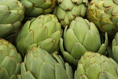 Many fresh raw artichokes as background, closeup