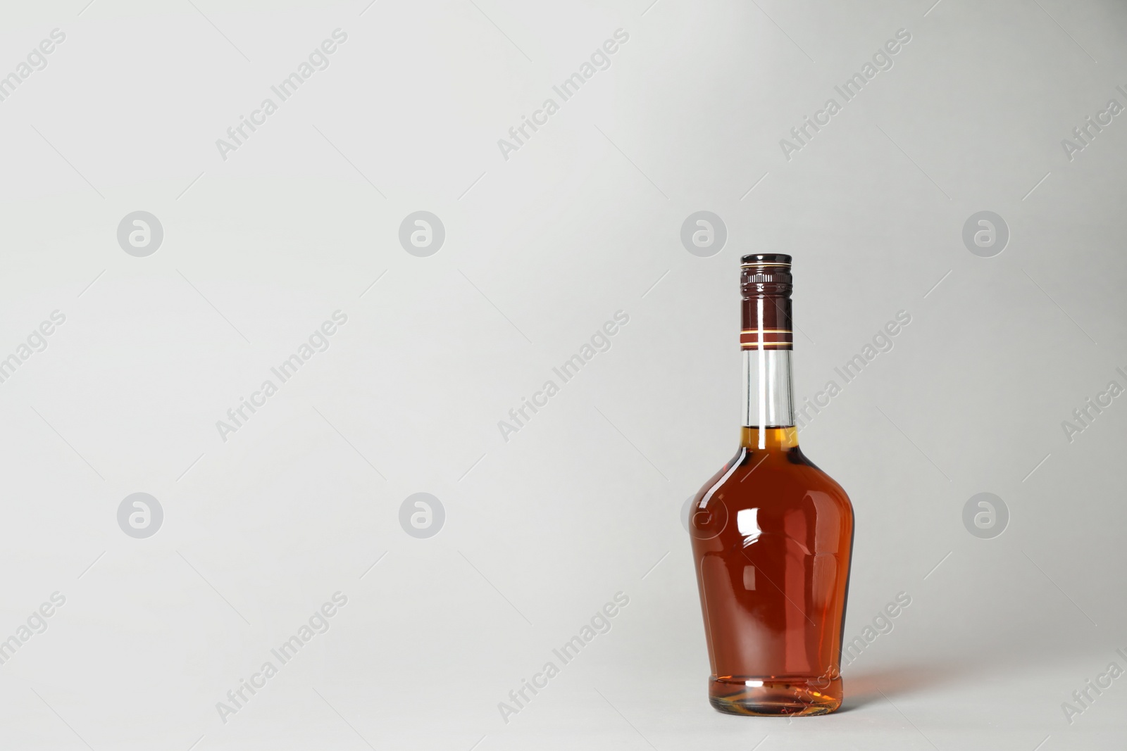 Photo of Bottle of alcoholic drink on grey background. Space for text