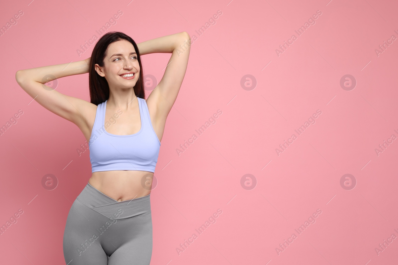 Photo of Happy young woman with slim body posing on pink background, space for text