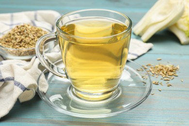 Photo of Aromatic fennel tea in cup on light blue wooden table, closeup