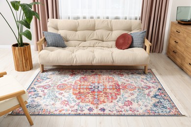 Photo of Beautiful rug, sofa and plant near window indoors