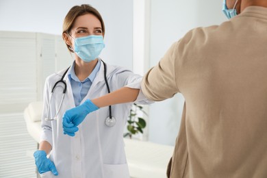 Photo of Doctor and patient doing elbow bump instead of handshake in clinic. New greeting during COVID-19 pandemic