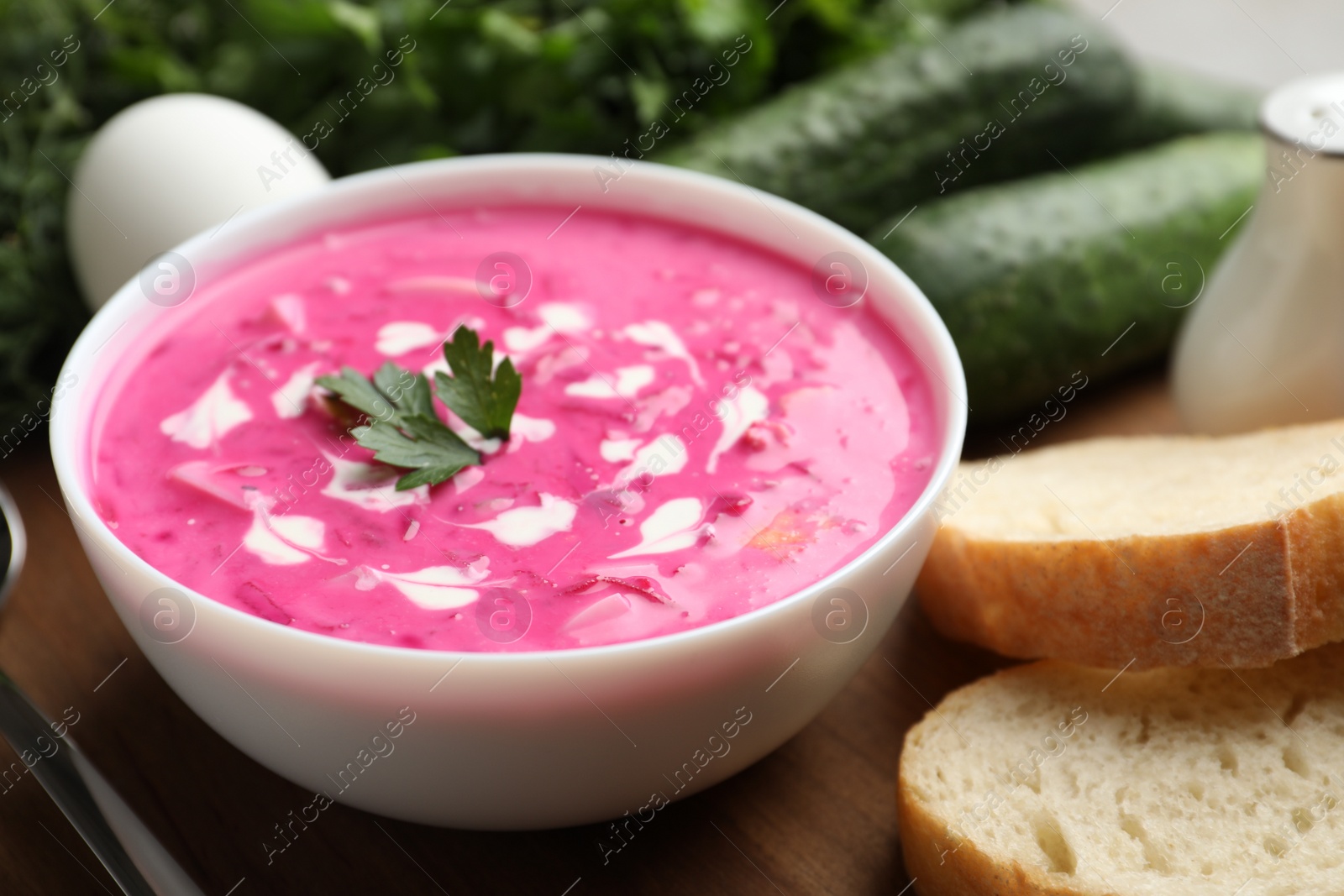 Photo of Delicious cold summer beet soup on wooden board, closeup