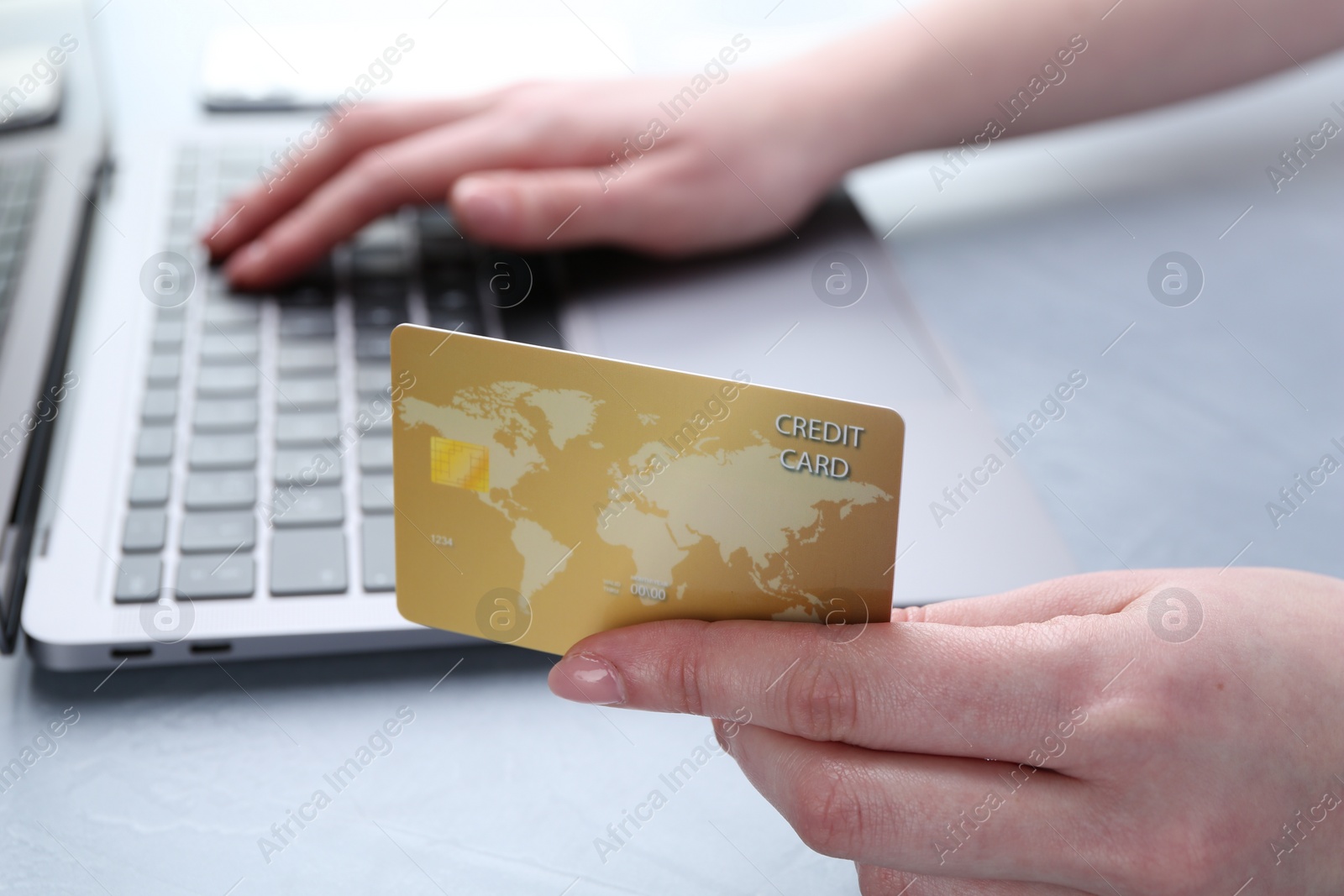 Photo of Online payment. Woman with laptop and credit card at white table, closeup