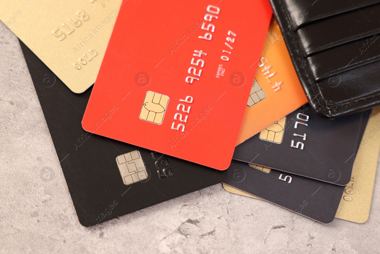 Photo of Many different credit cards and leather wallet on grey table, top view