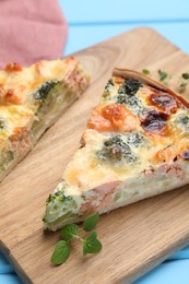 Photo of Pieces of delicious homemade quiche with salmon and broccoli on wooden board