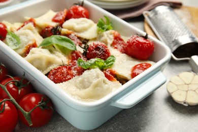 Photo of Tasty ravioli with tomato sauce served on grey table, closeup