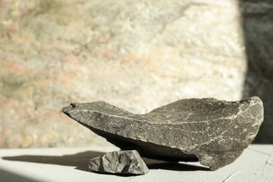 Photo of Presentation of product. Podium made of stones on light textured table. Space for text