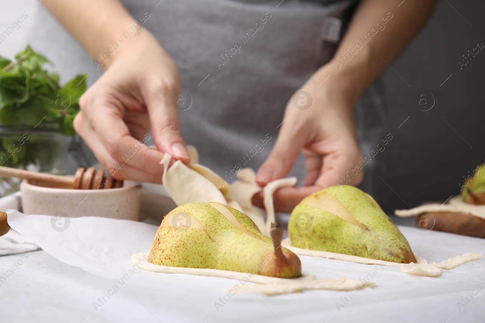 Photo of Woman making pastry with dough and fresh pears at white table, closeup